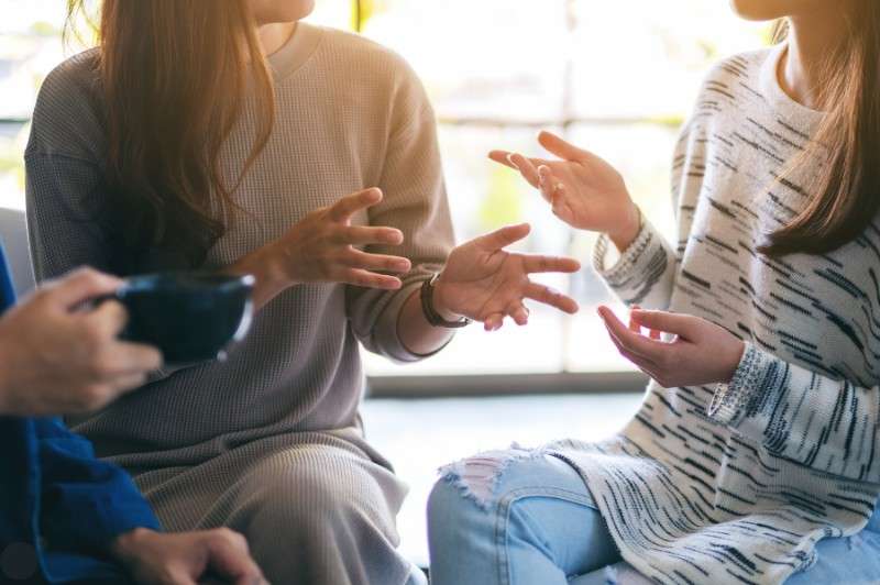 Two women discussing private health insurance options over coffee